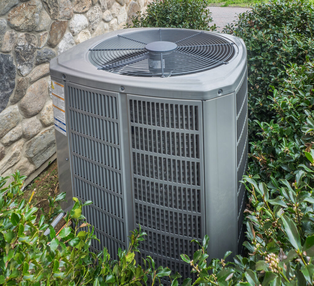 Heating and air conditioning unit in backyard of a residence.